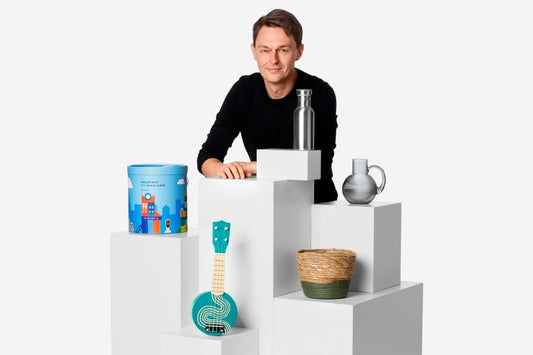 Flying Tiger Copenhagen CEO Martin Jermiin posing with various products on white pedestals.