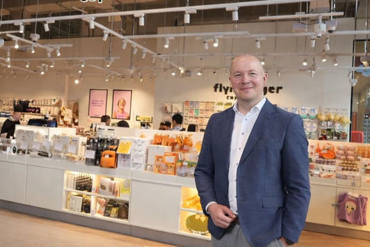 Smiling man in suit standing in a brightly lit retail store.