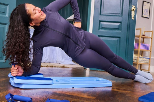Woman doing a side plank exercise on a fitness mat indoors.