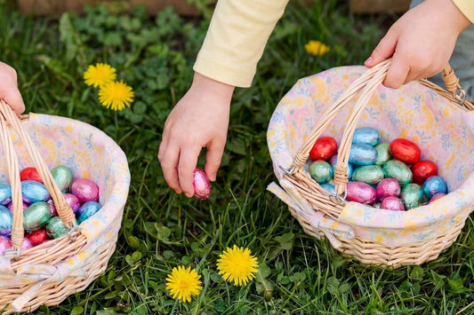 Children collecting colorful Easter eggs in woven baskets on grass.