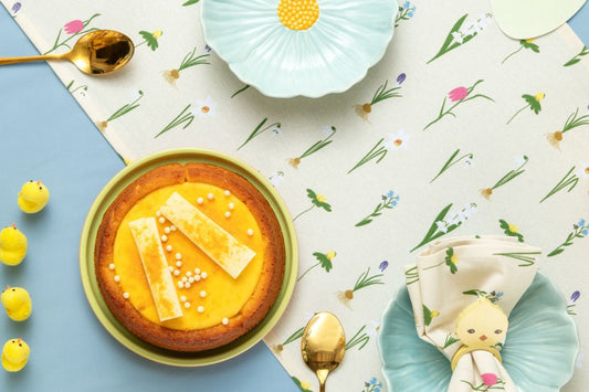 A dessert plate with flan, utensils, and floral-patterned tablecloth.