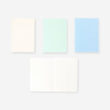 Set of four Flying Tiger Copenhagen A5 solid color office notebooks with vibrant covers and blank pages for note-taking.
