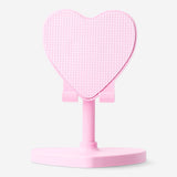 Pink heart-shaped Flying Tiger Copenhagen media smartphone stand resting on a desk with a phone placed on it.
