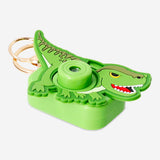 Flying Tiger Copenhagen projector camera gadget shaped like a green dinosaur showing colorful light projections.