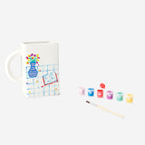 DIY ceramic book mug with paint from Flying Tiger Copenhagen, featuring a white mug shaped like an open book with colorful painted details.