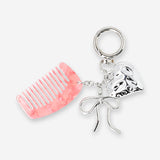 Colorful textile keyring with a hair comb and decorative charms, featuring vibrant patterns and playful design.