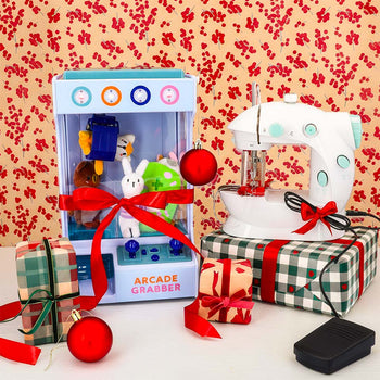 Flying Tiger Copenhagen toy arcade grabber and kids’ sewing machine displayed with festive Christmas gifts.