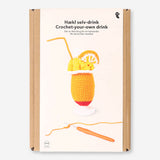Crochet tropical drink in vibrant colors, crafted as a DIY hobby project by Flying Tiger Copenhagen, displayed on a flat surface.