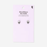 Silver skull stud earrings from Flying Tiger Copenhagen with textile backing, featuring small, detailed skull designs.