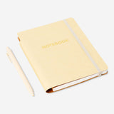 Butter yellow Flying Tiger Copenhagen office notebook with a matching ballpoint pen on a desk.
