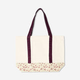 Textile shopper bag with floral pattern and burgundy strap from Flying Tiger Copenhagen, showing the bag's design and handles.