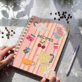 Flying Tiger Copenhagen office recipe book open to pages with colorful cooking and baking ideas, laid out on a desk.