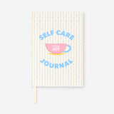 Flying Tiger Copenhagen self-care journal on office desk with open pages, featuring motivational prompts and a pen.