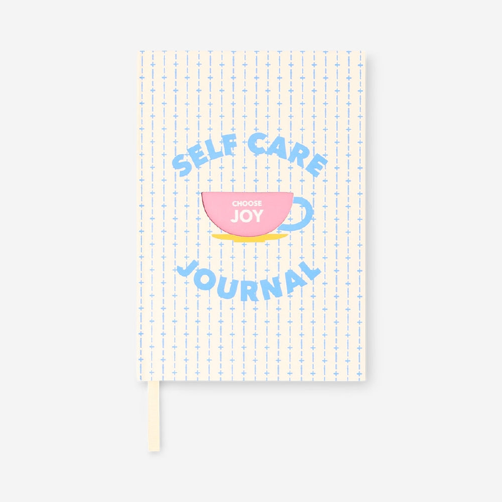 Flying Tiger Copenhagen self-care journal on office desk with open pages, featuring motivational prompts and a pen.