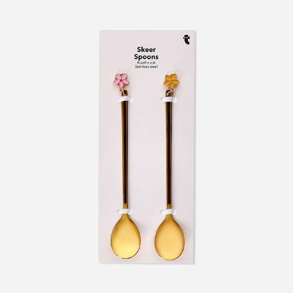 Two gold dessert spoons with floral decorations from Flying Tiger Copenhagen, featuring intricate flower details on each spoon.