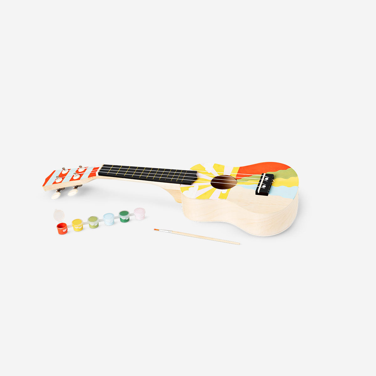 DIY ukulele kit with paint from Flying Tiger Copenhagen, featuring a wooden ukulele and colorful paint supplies for customization.