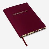Burgundy Flying Tiger Copenhagen office notebook with printed text on the cover, open showing lined pages inside.