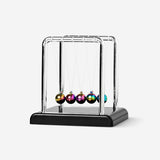 Small Newton's cradle gadget by Flying Tiger Copenhagen showing five metal balls swinging on strings.