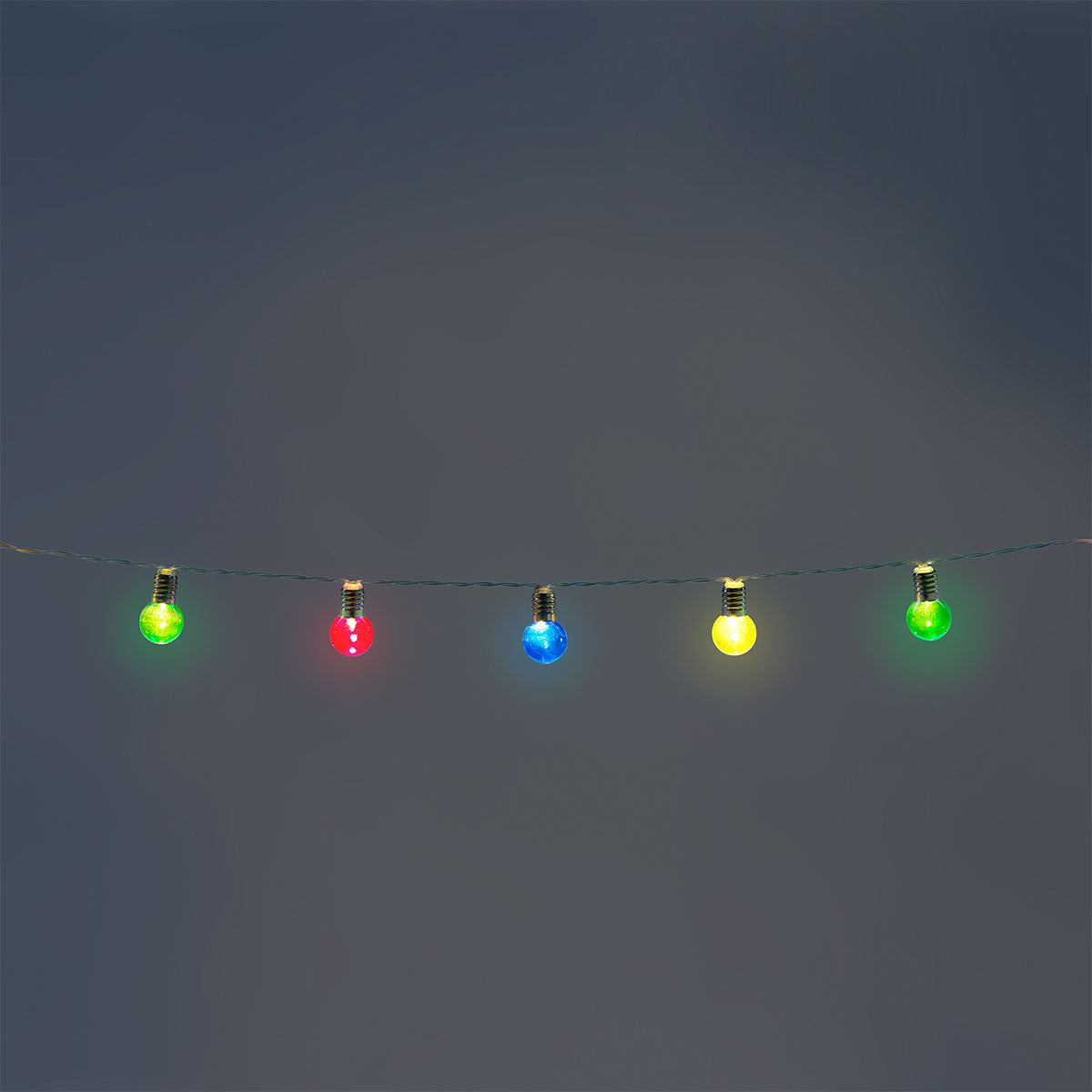 Colorful round bulbs outdoor string lights by Flying Tiger Copenhagen hanging in a backyard setting.