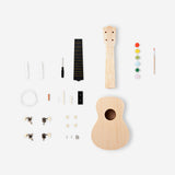 DIY ukulele kit with paint from Flying Tiger Copenhagen, featuring a small wooden ukulele and colorful painting supplies for hobby crafting.