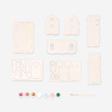 DIY wooden gingerbread house hobby kit by Flying Tiger Copenhagen, showing assembled miniature gingerbread house with detailed wooden parts.