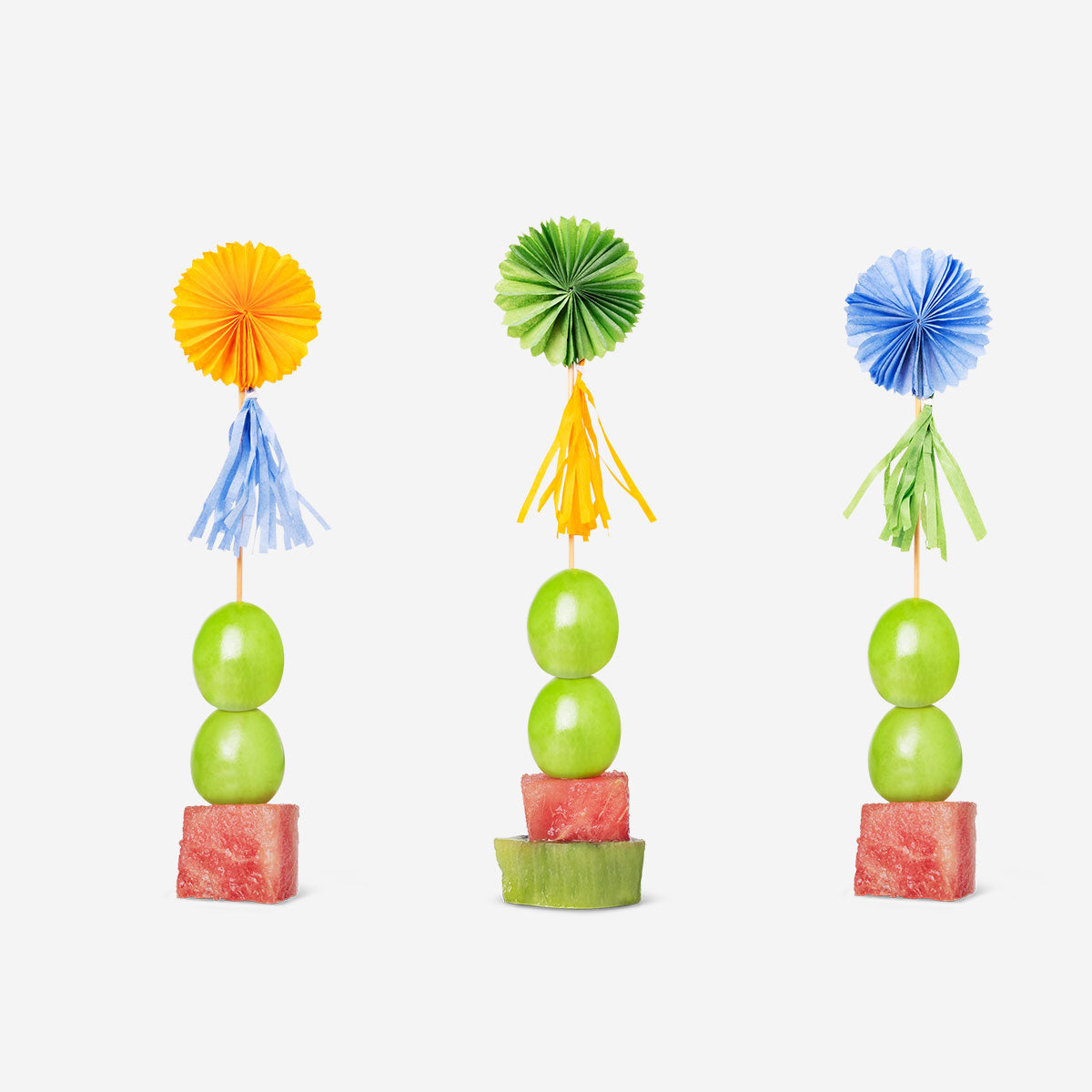 Set of three Flying Tiger Copenhagen party food picks with paper fans and tassels for festive appetizers and snacks.