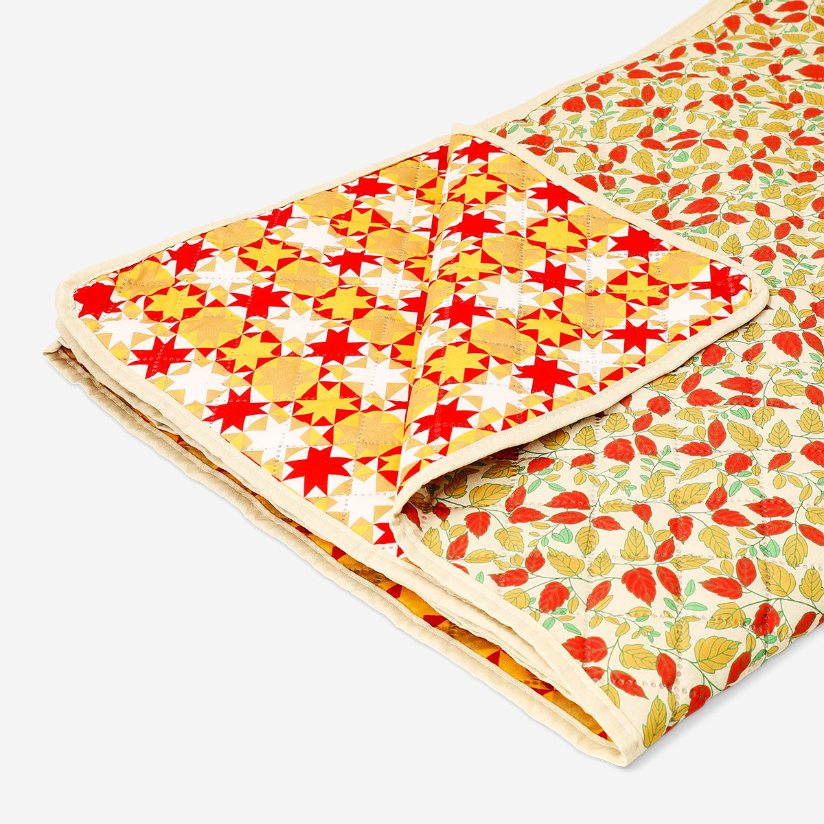 Quilted autumnal blanket by Flying Tiger Copenhagen, 170x130 cm, with warm, cozy fall-inspired patterned fabric on a bed.