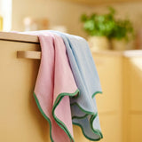 Set of two Flying Tiger Copenhagen kitchen tea towels with scalloped edges, featuring soft fabric and decorative hem detailing.