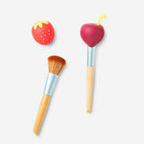 Two berry-shaped makeup brush covers in vibrant red and green, designed to protect and organize beauty brushes.