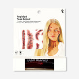 Fake blood for skin and temporary tattoos from Flying Tiger Copenhagen, shown spread on a flat surface with tattoo designs nearby.