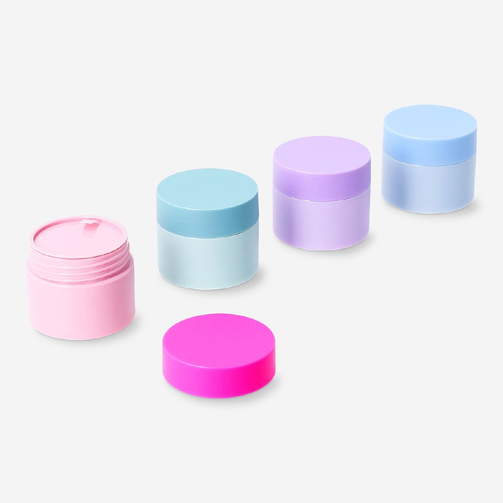 Set of four Flying Tiger Copenhagen travel jars with colorful stickers, perfect for organizing toiletries on the go.