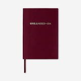 Burgundy Flying Tiger Copenhagen office notebook with printed text on the cover, ideal for writing and note-taking.