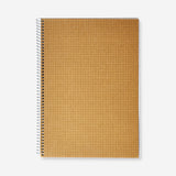 A4 spiral-bound grid notebook with a craft paper cover from Flying Tiger Copenhagen, showing the spiral binding and textured cover.