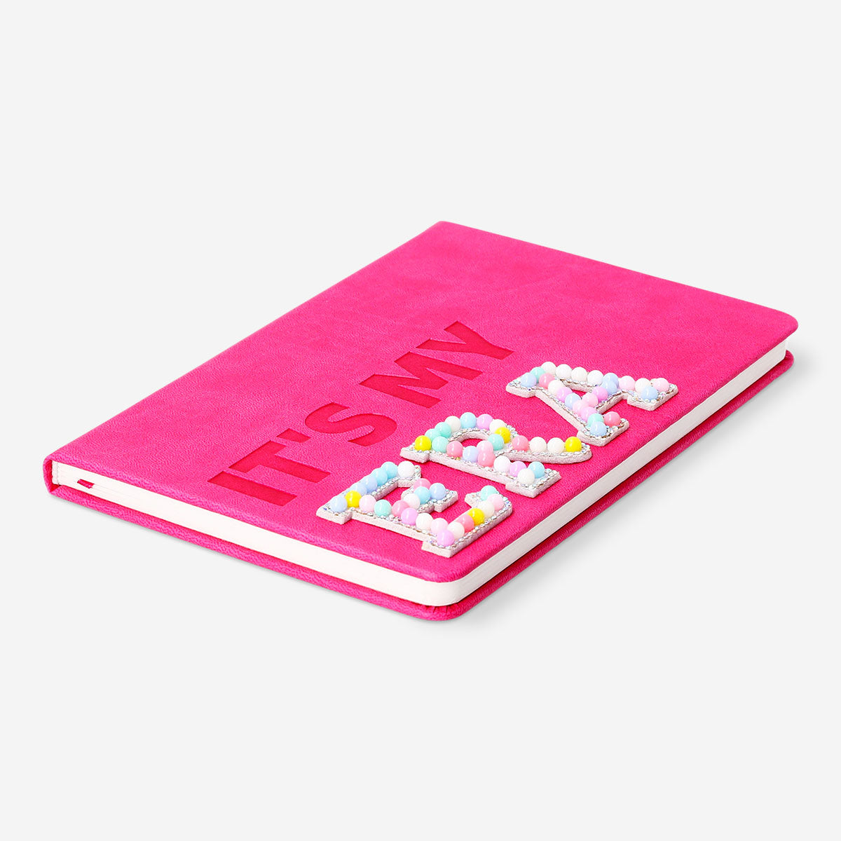 Pink A5 office notebook with pom poms from Flying Tiger Copenhagen, featuring a soft cover and decorative pom pom accents.