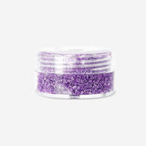 Purple glitter eyeshadow flakes from Flying Tiger Copenhagen, close-up view showing sparkly, flaky cosmetic product for eye makeup.