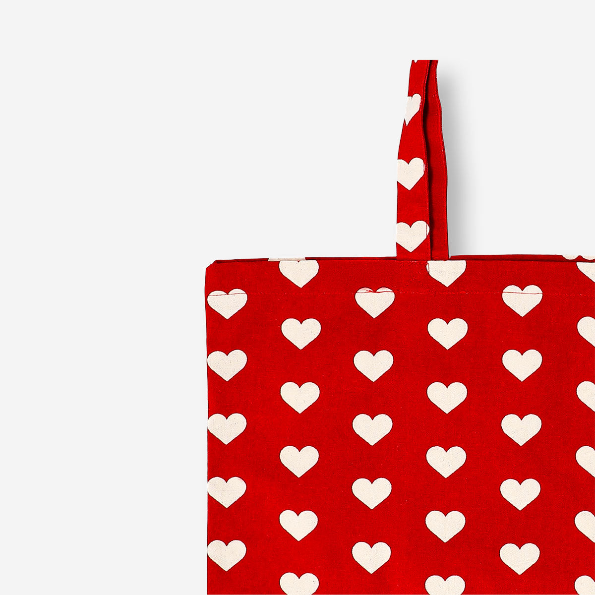 Red textile tote bag with heart patterns from Flying Tiger Copenhagen, featuring a spacious design and sturdy handles.