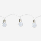 Outdoor string lights with clear bulbs, ideal for home decor, by Flying Tiger Copenhagen, hanging outdoors in a cozy setting.