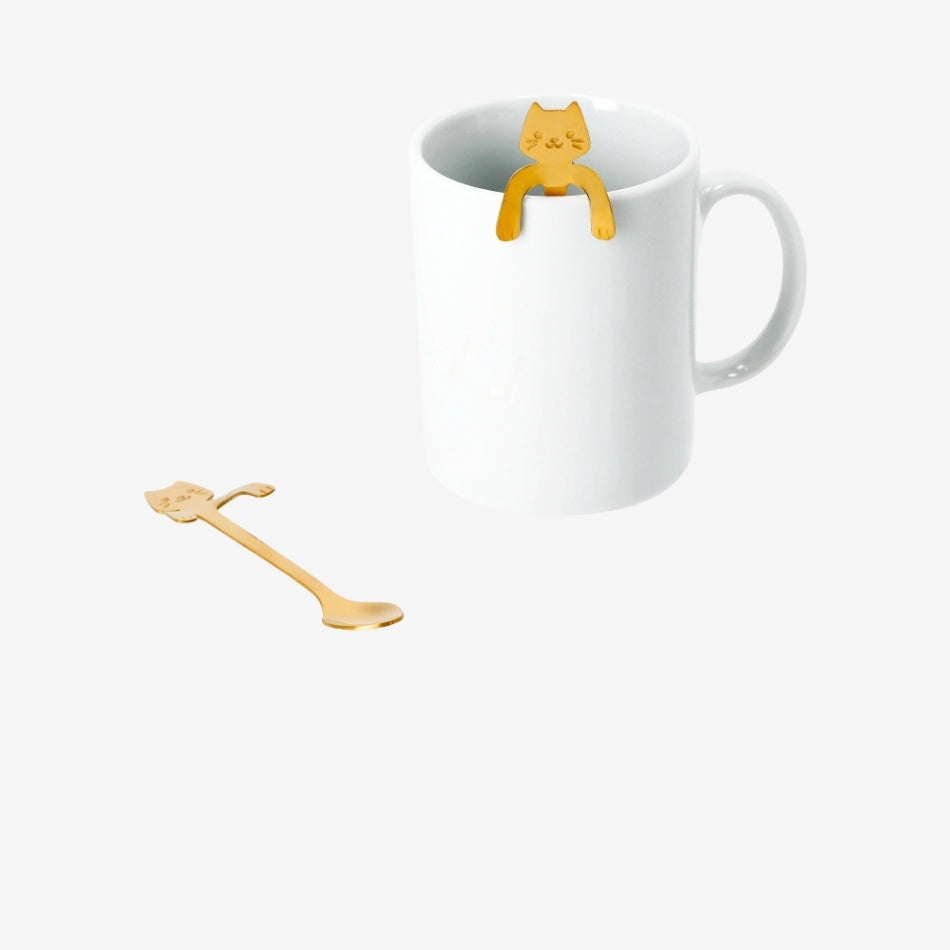 Two gold cat-shaped spoon decorations for hanging on mugs, designed for kitchen use by Flying Tiger Copenhagen.