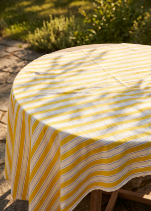 Yellow striped tablecloth from Flying Tiger Copenhagen, 140x220 cm, featuring vibrant yellow and white stripes on a fabric surface.