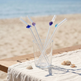 Four glass kitchen straws with colorful fish and seashell decorations, perfect for ocean-themed drinkware.