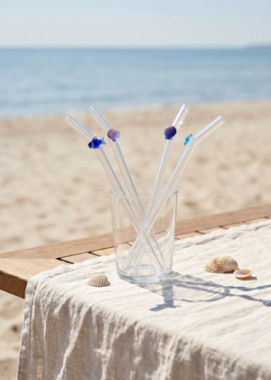 Set of four glass kitchen straws with colorful fish and seashell decorations, ideal for eco-friendly beverage drinking.