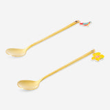 Two gold dessert spoons with tropical flower decorations from Flying Tiger Copenhagen for elegant kitchen use.