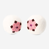 Two Wool laundry balls with flower motifs from Flying Tiger Copenhagen, used for eco-friendly fabric softening and laundry care.