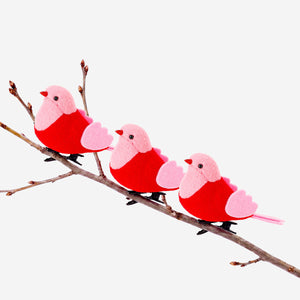 Decorative pink and red bird ornaments for home decor by Flying Tiger Copenhagen, showcasing colorful bird figures on a neutral background.