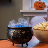Color-changing fog machine gadget shaped like a 12 cm cauldron from Flying Tiger Copenhagen, with swirling fog and glowing lights.