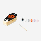 DIY wooden coffin hobby kit with paint from Flying Tiger Copenhagen, showing painted wooden coffin and craft supplies.