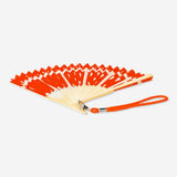 Foldable bamboo fan with orange textile print and strap by Flying Tiger Copenhagen, showcasing vibrant design and compact portability.