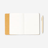 Butter yellow office notebook with a matching ballpoint pen from Flying Tiger Copenhagen, open showing lined pages.
