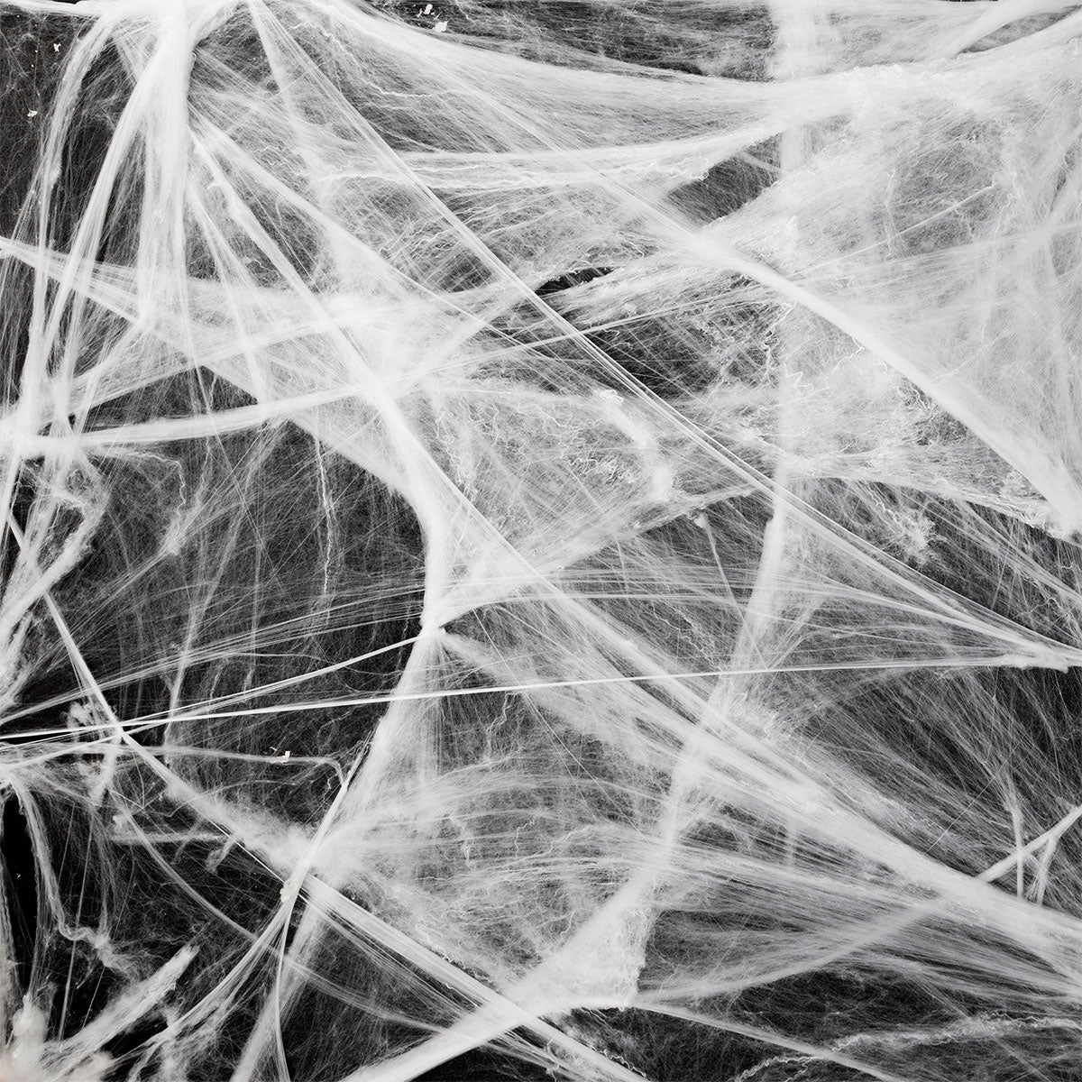 White spider cobweb decoration for parties, measuring 70x400 cm, by Flying Tiger Copenhagen, shown hanging with a spooky theme.