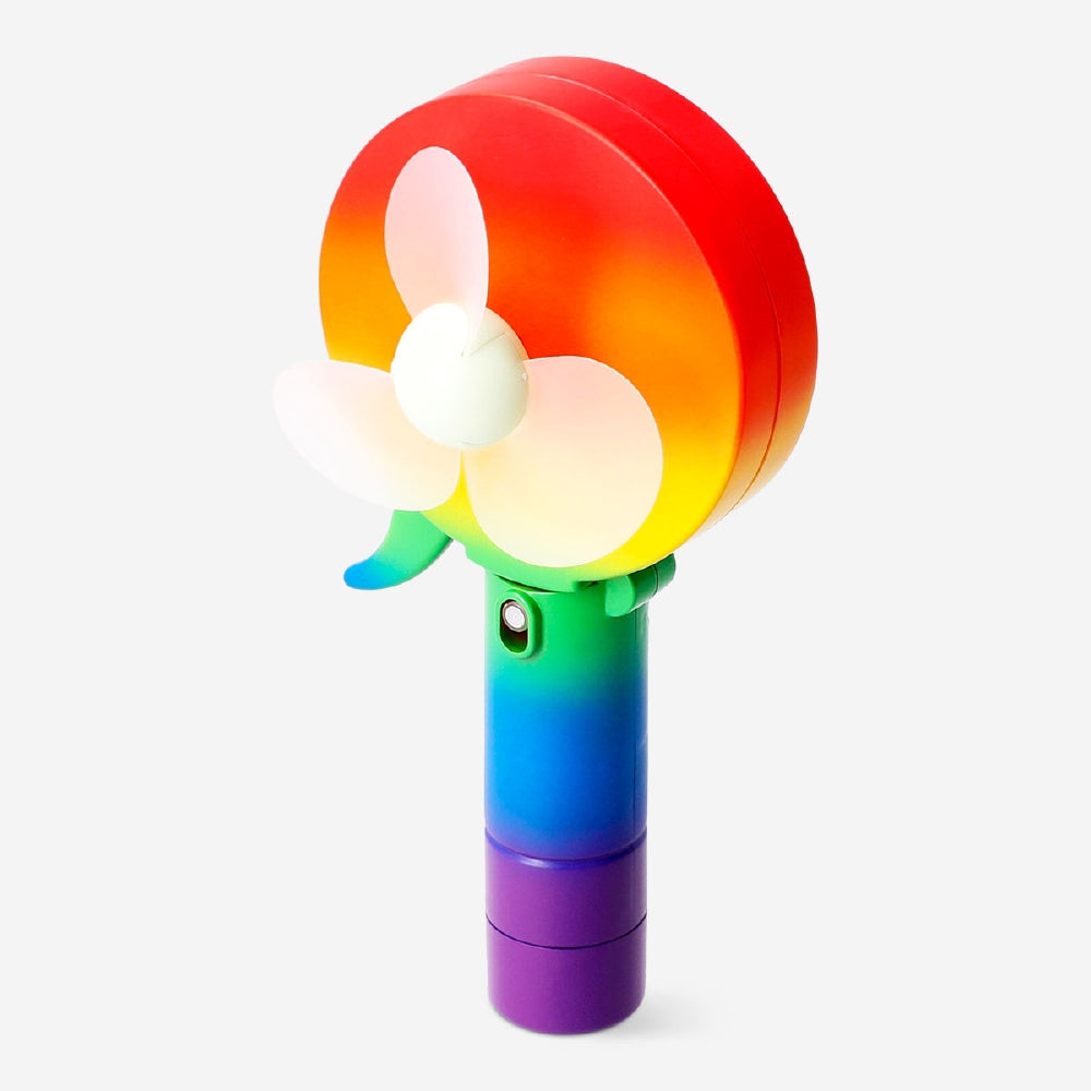 Rainbow coloured handheld fan gadget by Flying Tiger Copenhagen, showing vibrant rainbow stripes and compact design.